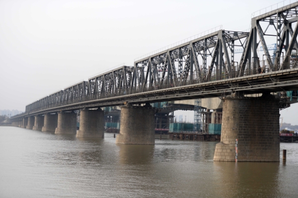 新华社照片，哈尔滨，2014年4月20日
    百岁松花江最早江桥退役
    这是哈尔滨滨洲铁路桥（4月19日摄）。
    日前，被哈尔滨人亲切地称为“老江桥”的松花江滨洲铁路大桥正式暂停使用。不少市民和游客登上这座桥，与这座百年历史的“钢铁巨人”合影留念。
    滨洲铁路桥又称哈尔滨中东铁路桥，1900年5月16日正式动工，1901年8月22日全面完工，同年10月2日交付使用，是松花江上最早的铁路大桥，也是哈尔滨的第一座跨江桥梁。该桥由沙俄时代桥梁专家、中东铁路工程局桥梁总工程师连多夫斯基亲自监督，工程师阿列克谢罗夫负责施工。全长949米，桥墩用花岗岩砌筑，十分坚固。1962年7月，由东北铁路工程局设计并进行了该桥梁的加固。
    据了解，滨洲铁路桥已于2008年纳入第三次全国文物普查范围，是不可移动文物，将作为文物完整保留，成为哈尔滨旅游观光桥。
    新华社记者王凯摄