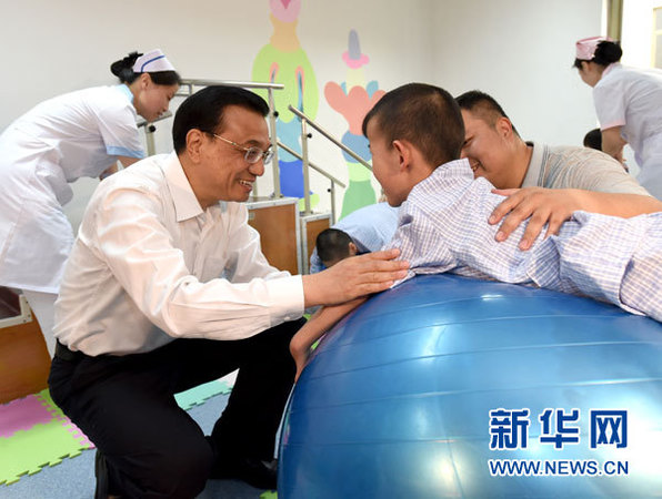 这是李克强与进行康复训练的患儿交谈。 新华社记者马占成摄