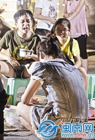 边吃臭豆腐边和客人推介的孩子，一脸认真