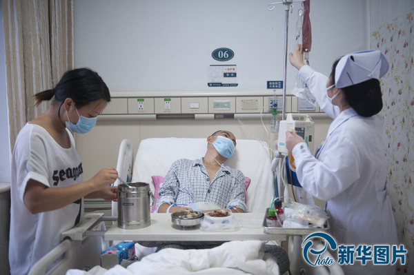 李真病床旁，向华与护士各站一边，向华把饭菜摆上小桌，护士换药瓶，李真靠在床上看着护士换药瓶，没有看他平时最爱吃的香干炒肉。