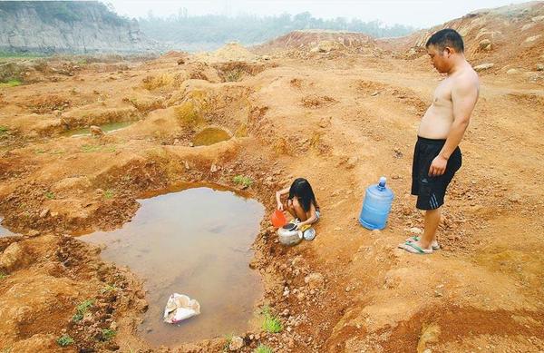 7月30日，大河报记者奔赴严重干旱的平顶山市宝丰县，看到旱情如同烈火，抗旱十万火急。父女俩，在已经枯竭的上李庄水库库底取水，这里离他们的家两公里。 记者 李红汛 实习生 余文龙 文 记者 平伟 实习生 高阳 摄影 图片来源：大河网
