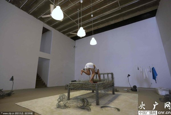 　2014年8月11日，北京，中国女艺术家周洁在北京现在画廊的展厅睡在一个未完成的铁丝床上，这一艺术项目被命名为“36天”，而这36天里，她可以正常进食、洗漱、如厕，以及玩手机等。