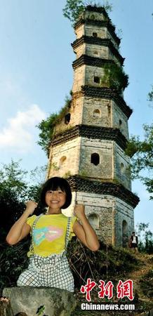 图为8月25日，“无腿女孩”蒋张子怡在半边古塔前，手握双拳，开心表示自己和塔一定会坚挺下去。卓忠伟 摄