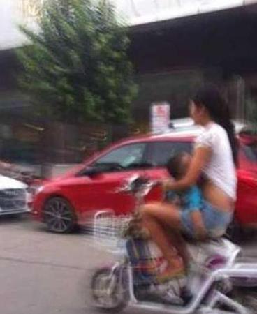 妈妈边骑车边给孩子喂奶。