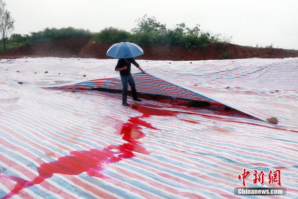 2014年9月15日，河南洛阳汝阳县马兰河因为污染变成一条“红河”，“红水”顺着山坡一直流到山下，而“红水”的源头正是附近一山顶的染料厂残留处理池。图为山顶涂料厂未处理的残渣被塑料布覆盖，因多日降雨，染红的雨水从山流下。