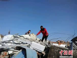 图为房主在被拆的房屋上寻找被埋的现金 图为房主在被拆的房屋上寻找被埋的现金