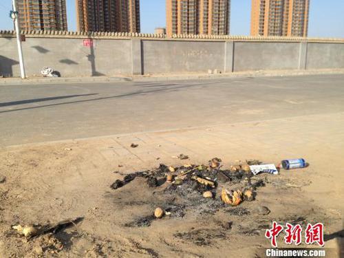 亲人在何建华遇害处燃烧的纸钱和祭品。 王天译 摄