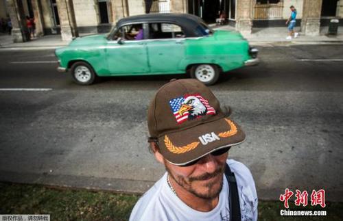 图为当地时间2月3日，古巴首都哈瓦那，一个行人头戴印有美国国旗的帽子行走在街头。