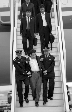 5月9日，在北京首都国际机场，李华波（前中）被押解下飞机。新华社发