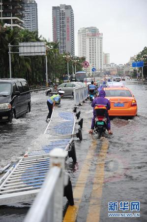 6月23日，在海南省三亚市，一位交警试图扶起倒地的护栏。今年第8号台风“鲸鱼”已于6月22日18时50分左右在海南省万宁市沿海登陆，台风给三亚带来了强风降雨天气，影响市民正常出行。新华社发（沙晓峰 摄）