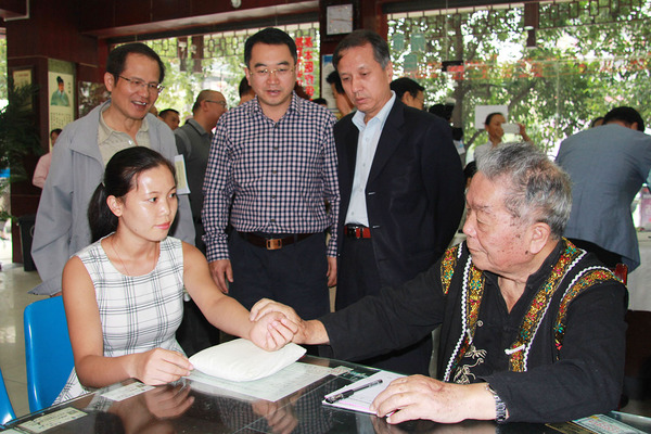 83岁的贵州老苗医熊文美给患者号脉，黄元河、陆洪光、安阿玥（从左至右）驻足了解。