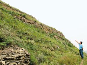 考古人员介绍石峁遗址的核心区“皇城台”边坡上的高大墙体(资料图片)  考古人员介绍石峁遗址的核心区“皇城台”边坡上的高大墙体(资料图片)