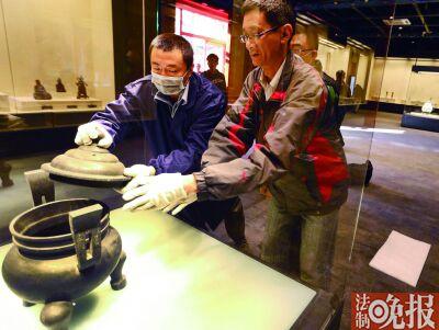 工作人员将清双天官帽耳带盖蹄足铜炉放置在展台上  工作人员将清双天官帽耳带盖蹄足铜炉放置在展台上