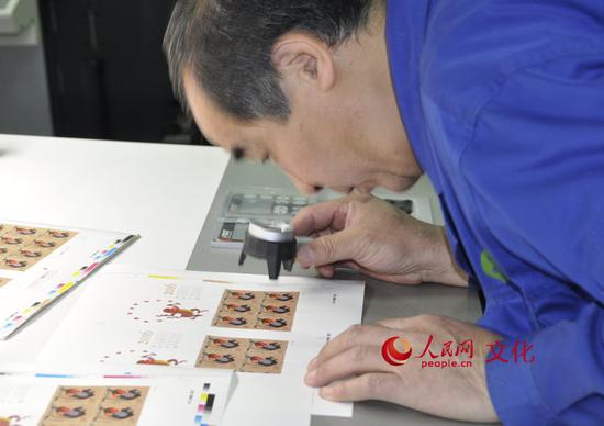 印刷车间里的工作人员正在用放大镜检查印刷效果。（人民网 王鹤瑾 摄）
