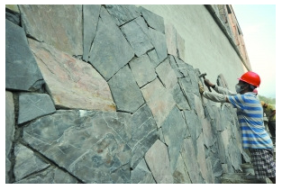 工人正在将一块块英石片贴上外墙 工人正在将一块块英石片贴上外墙