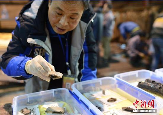 考古领队杨军在看刚刚出土的文物。 郭晶 摄