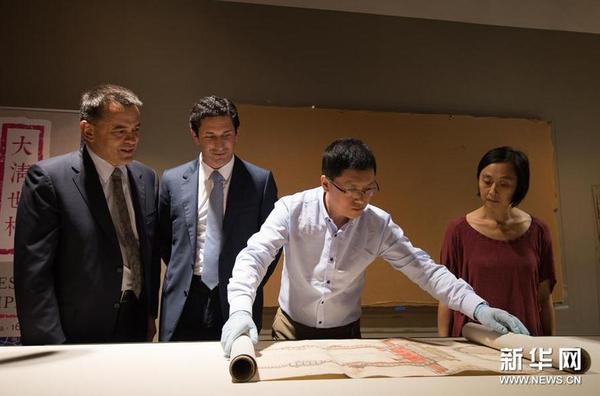 12月8日，在位于澳大利亚堪培拉的澳大利亚国家图书馆展厅，来自中国国家图书馆古籍部文献修复组的朱振彬（右二）展开《大清门至坤宁宫中一路立样糙底》。