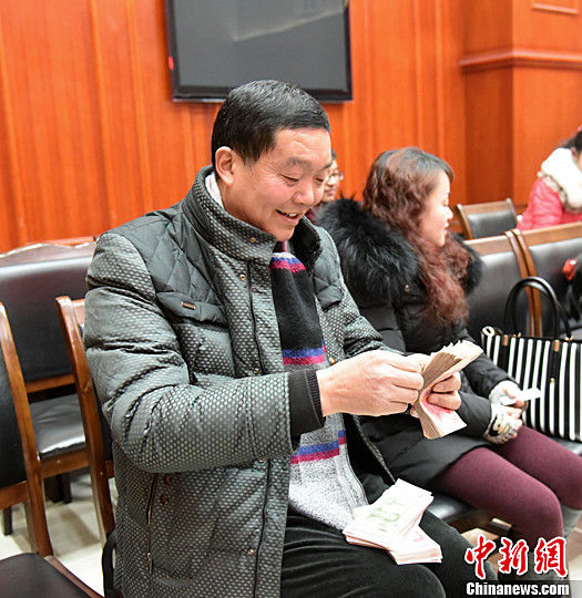 图为农民工清点自己领到的钱。中新社记者