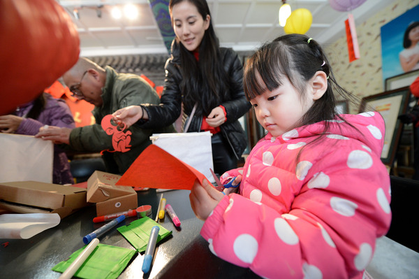 2A 小朋友在妈妈的陪同下剪纸做灯笼。