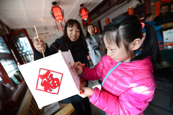 14A图为孩子们在家长的陪同下扎灯笼，描画图案。