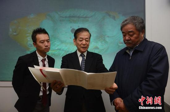 　　3月28日，牟田口章人（图中）向内蒙古博物院院长（图右）介绍捐赠的文献。当日，日本帝塚山大学文化创造学科教授牟田口章人在呼和浩特，向内蒙古博物院捐赠了辽代文物“双鱼形琉璃釉建筑构件”。据悉，该文物是他在日本自己出资购得，同时他还代友人捐助了辽代历史研究文献。中新社记者 刘文华 摄