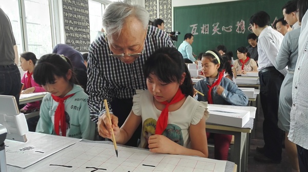 政协委员“手把手”给孩子们进行书法指导。