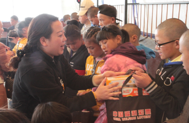 区福彩中心主任唐慧为孩子们发放慰问品