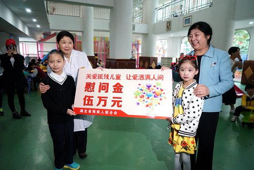 图为省残工委副主任、省残联党组书记、理事长陶慧芬委武汉市儿童福利院孤残儿童送去慰问金