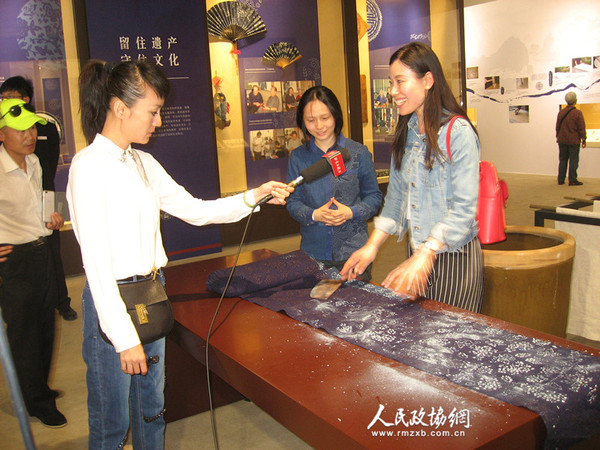 有关媒体现场采访正在中国园林博物馆布上青花——南通蓝印花布艺术展上体验蓝印花布制作工艺的观众。梓涵摄影报道_副本