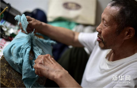 6月5日，张奎老人将雕刻皮影的纸模板紧紧地捆在包裹里