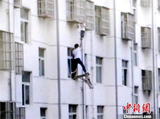 几名业主固定板凳，一名业主站上板凳托举男孩双脚 宋俊初 摄