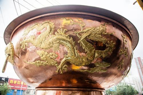 据介绍，这个火锅是按照真实火锅的尺寸等比例放大制作的，高5.55米，直径5.35米，总重量3.3吨，耗时两个多月量身订制，通体铜质，花费40余万人民币。