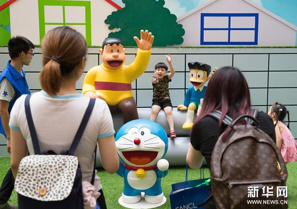 7月31日，一名小朋友在展出的卡通造型旁拍照。