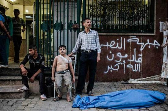 　　“他的父亲去世了，而他还不了解这意味着什么”。 12岁的艾哈迈德（Ahmed）和他的叔叔在他父亲的尸体旁等待，他的父亲被飞向阿勒波（叙利亚）的炮弹袭中，艾哈迈德的后背也被弹片划伤了。 摄影师：尼科尔·唐