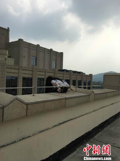 图为“盘踞”无锡某商场楼顶多日的长发人体模型?！∏蒯?摄