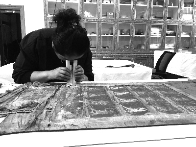 京红正在仔细观察唐卡破损的部位 京红正在仔细观察唐卡破损的部位