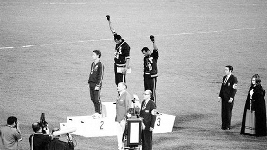 史密斯和卡洛斯在领奖台上举起戴着黑色手套的拳头