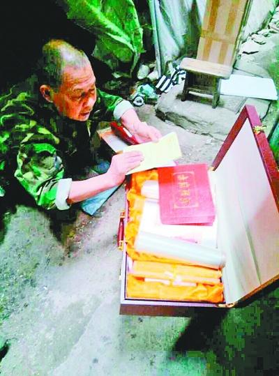 　代爹爹展示收到的“纪念章”和“十大名画”。