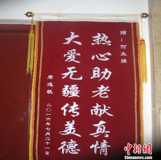 唐逸敏侄女赠送的锦旗挂在社区走廊的墙壁上。　杨东 摄