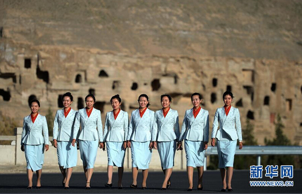 身着全新工作制服的莫高窟讲解员从洞窟前走过。新颖别致的服装既方便了游客识别工作人员，也成为景区内一道靓丽的风景。新华社记者陈斌 摄 图片来源：新华网