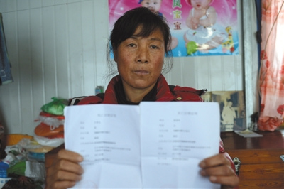 12月13日下午，杨福珍手捧着大儿子和儿媳妇的死亡证明。2012年8月4日凌晨，暴雨导致的泥石流袭击了岫岩县南马峪村。杨福珍失去了丈夫、大儿子和大儿媳。