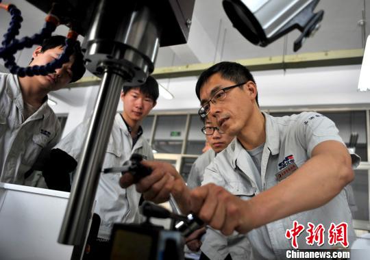 资料图:一名老师在指导学生学习数控机床的操作知识 资料图:一名老师在指导学生学习数控机床的操作知识