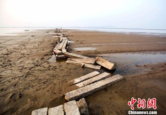 　　近年来，当鄱阳湖水位下降至枯水位时，石桥就会露出水面，成为当地一景。图为游人在古桥上行走。12月23日摄　傅建斌　摄
