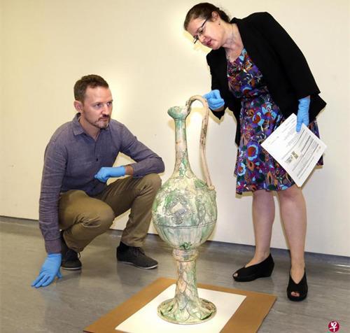 　　代表纽约亚洲学会的普罗瑟博士（右）正在检验即将装箱运往美国的唐代白釉绿彩高足把壶和绿釉龙首榫。左为亚洲文明博物馆的史蒂芬·墨菲博士。（新加坡《联合早报》/周柏荣 摄）