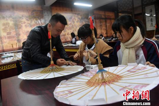 课堂上，严磊手把手地教导学生如何制作油纸伞?！÷烂?摄