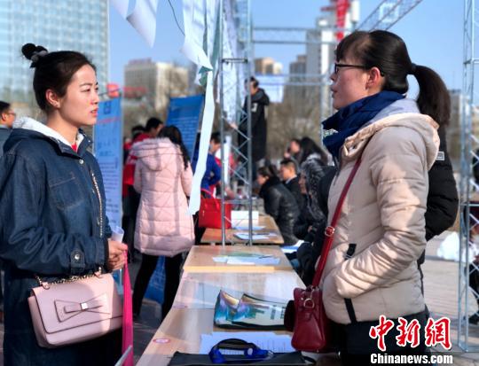 图为一名女大学生拿着自己的简历与用工单位负责人面对面交流，咨询应聘岗位的详细信息?！∷镱?摄