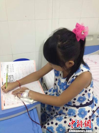 图为珊珊在医院一边输血一边写作业。 家属供图