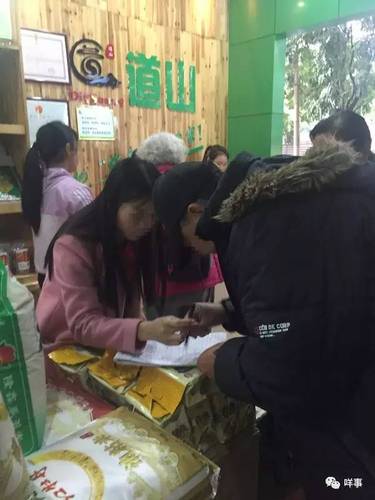 值班的业务员正为一名老人登记会员资料并派发团购券。