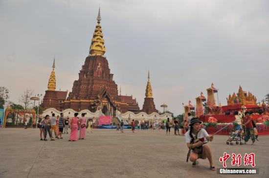 4月13日，云南西双版纳“告庄西双景”内，在金塔前留影的游客?！案孀魉啊蔽鲇?，意为“九塔十二寨”，位于澜沧江畔，占地1200亩的景区内傣式风格浓郁。自2012年开业至今，年接待游客量已经突破400万人次，2015年春节期间，日均游客人数突破10万人次，成为云南旅游新地标。 <a target='_blank' href='http://www.chinanews.com/'>中新社</a>记者 任东 摄