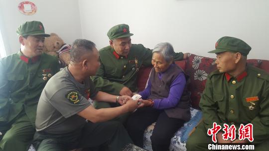 图为老兵们将慰问金送到门二柱母亲手中?！÷佬掠?摄